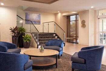 A modern hotel lobby with a curved sofa, a round coffee table, and a large window offering a view of the city. at SpringHill Suites Charleston Riverview 