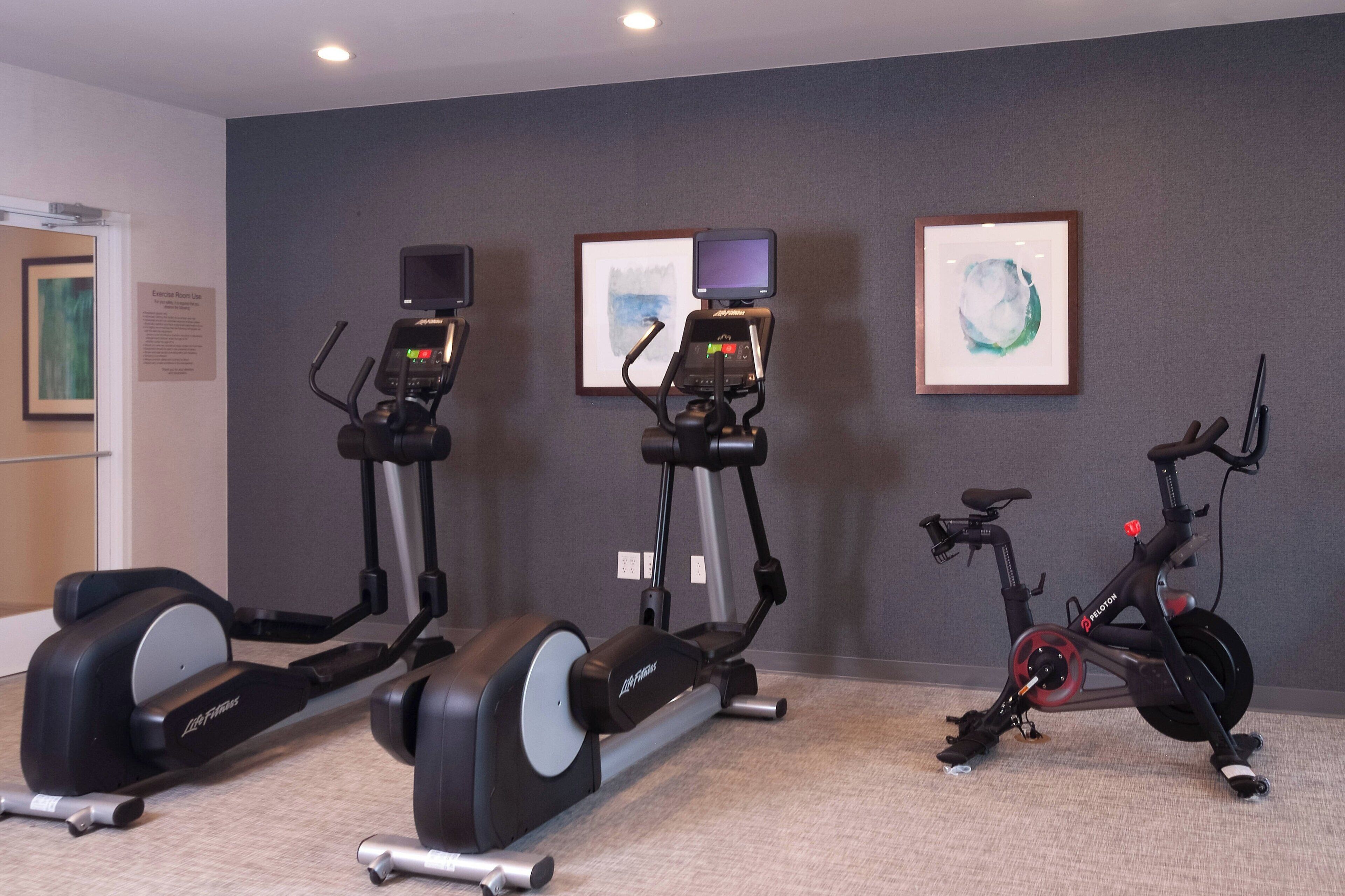 Three exercise machines in a room with grey walls and a carpeted floor.