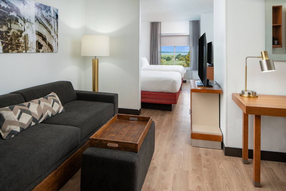 A hotel room with a sofa, a bed, a desk, and a TV.