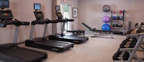 A gym with treadmills, exercise balls, and dumbbells.