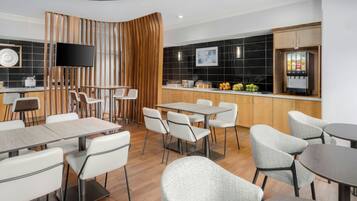 A modern restaurant with a variety of seating options, including tables and chairs, and a kitchen area with a beverage dispenser.