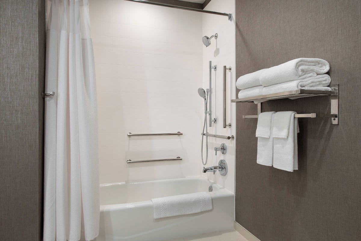 A modern bathroom with a bathtub, shower, and towel rack.