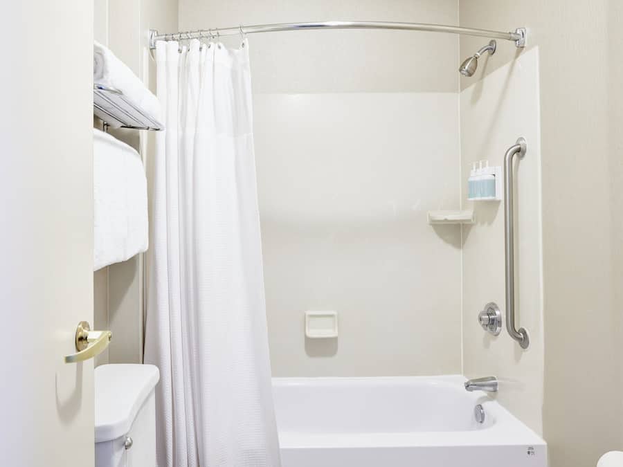 A modern bathroom with a shower, toilet, and a grab bar.