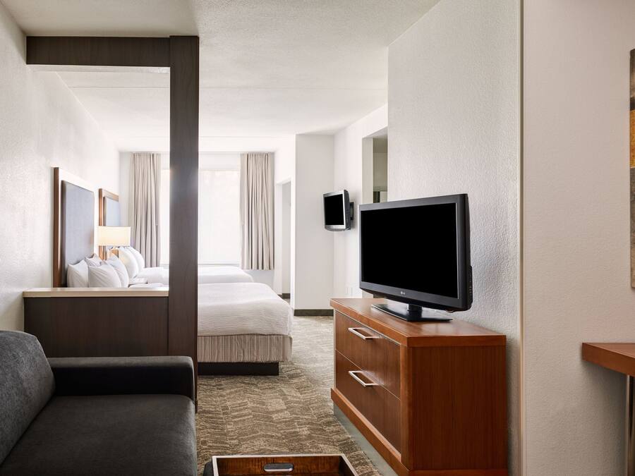 Een hotelkamer met een bed, een televisie op een houten kast, een bank en een kleine tafel.