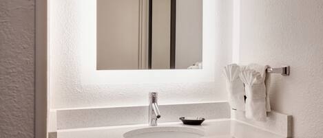 A bathroom with a white sink, a mirror, and a towel rack.