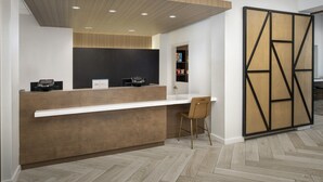 Ein Empfangsbereich mit einem Holztresen, einer weißen Theke und einem Stuhl. Eine schwarze Wand mit geometrischem Muster und eine Holzwand mit einem geometrischen Design.