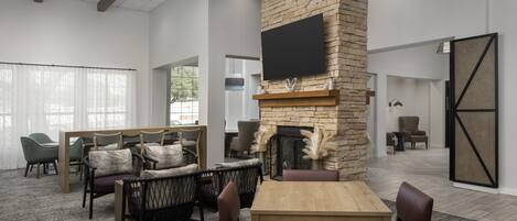 A spacious lounge area with a stone fireplace, comfortable seating, and a flat-screen TV mounted on the wall.