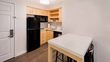 A compact kitchen with a refrigerator, microwave, sink, and wooden cabinets.