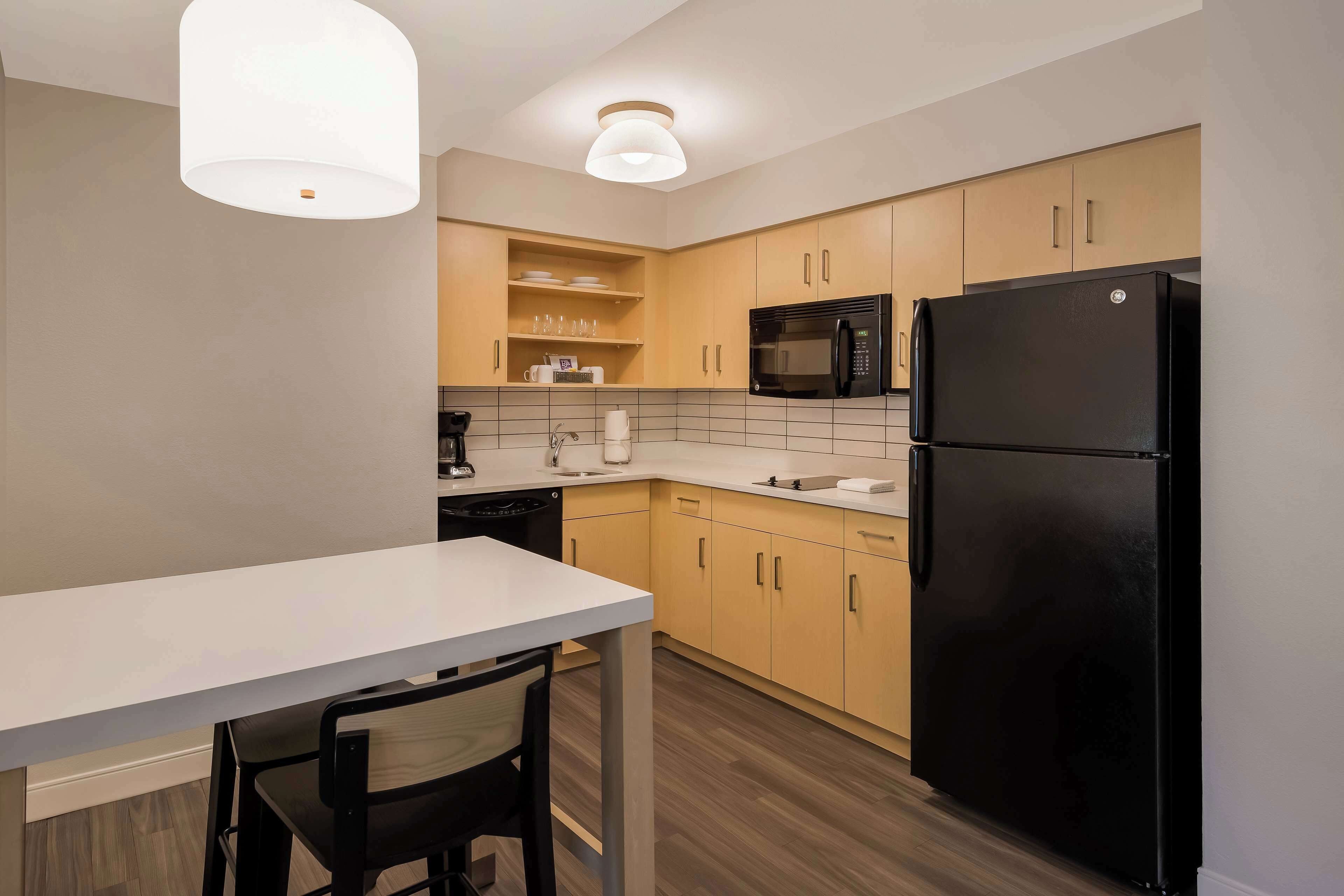 A modern kitchen with a white countertop, black appliances, and wooden cabinets.
