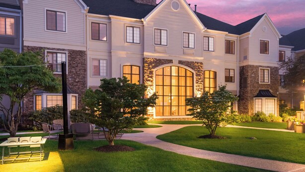 A multi-story residential building with a stone facade, large windows, and a well-maintained lawn.