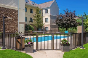 A swimming pool surrounded by a fence, with a building in the background. - Sonesta ES Suites Andover Boston (Andover)