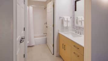 Un baño con bañera, ducha y lavabo con espejo.