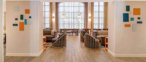 A modern lounge area with a wooden floor, contemporary furniture, and abstract wall art.