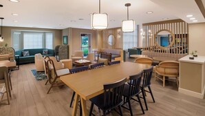 A modern living room with a large wooden dining table, comfortable seating, and a view of the outdoors.