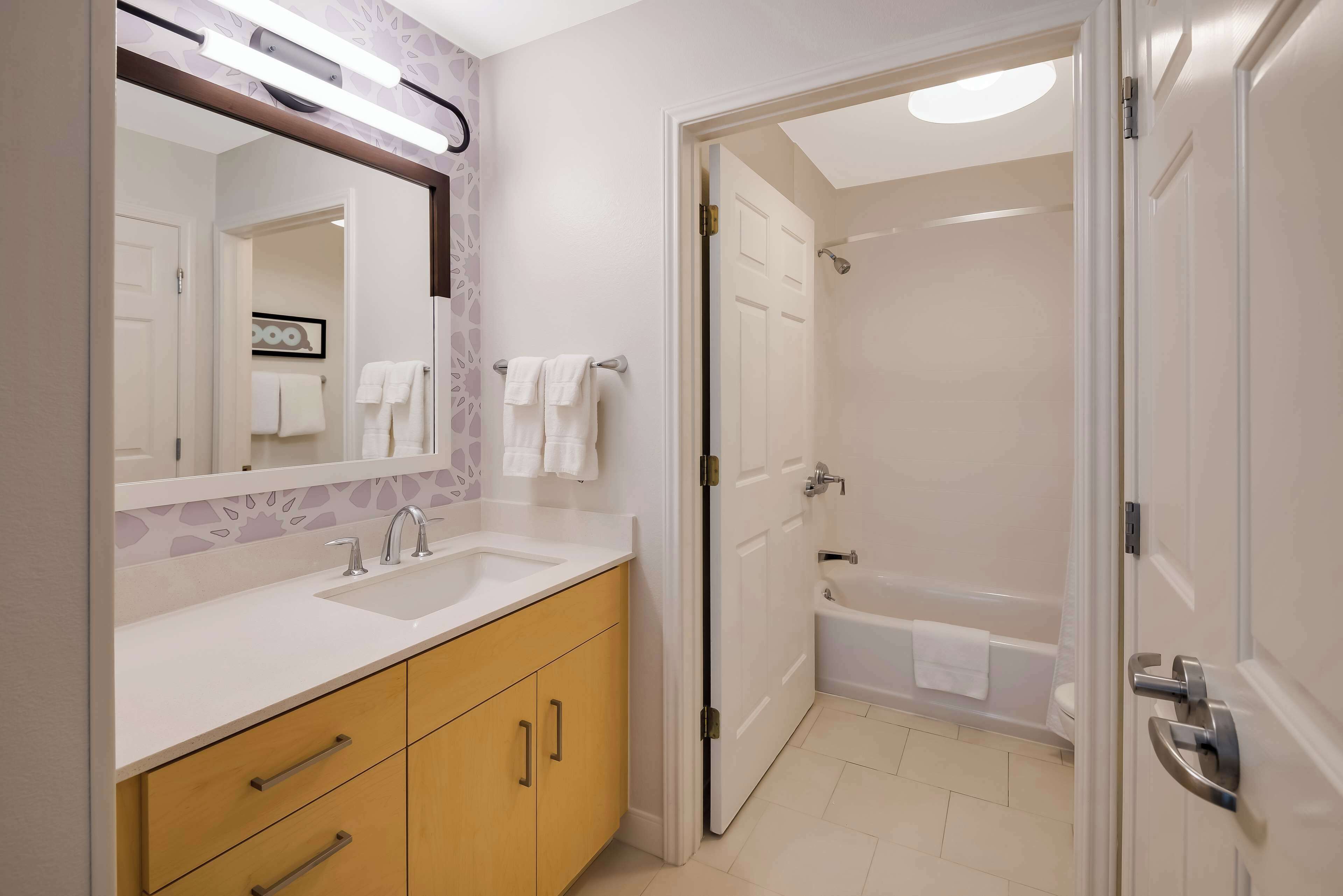 A modern bathroom with a double sink vanity, a large mirror, and a walk-in shower.