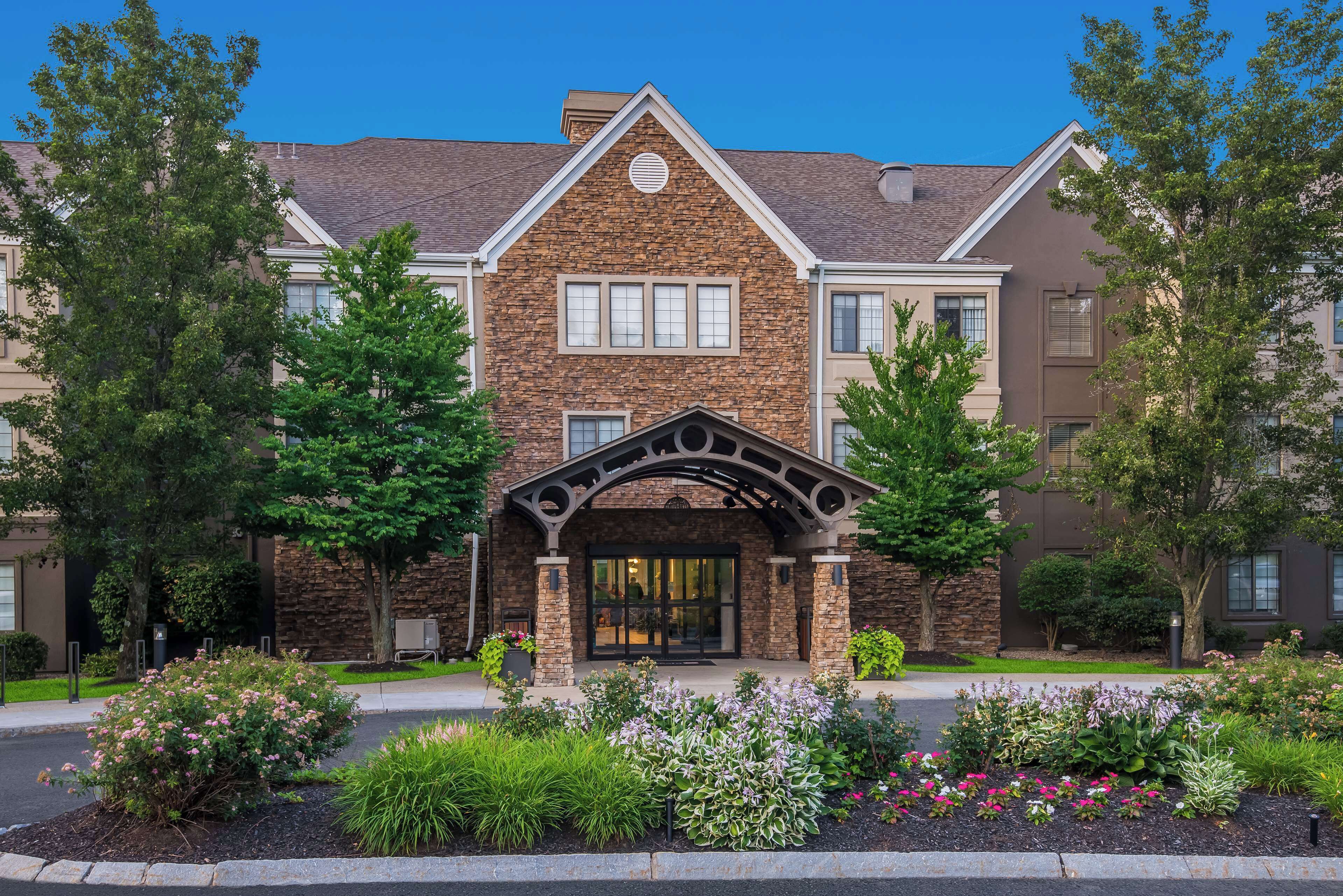 A multi-story building with a stone facade, a central entrance with a decorative arch, and a landscaped garden in front.