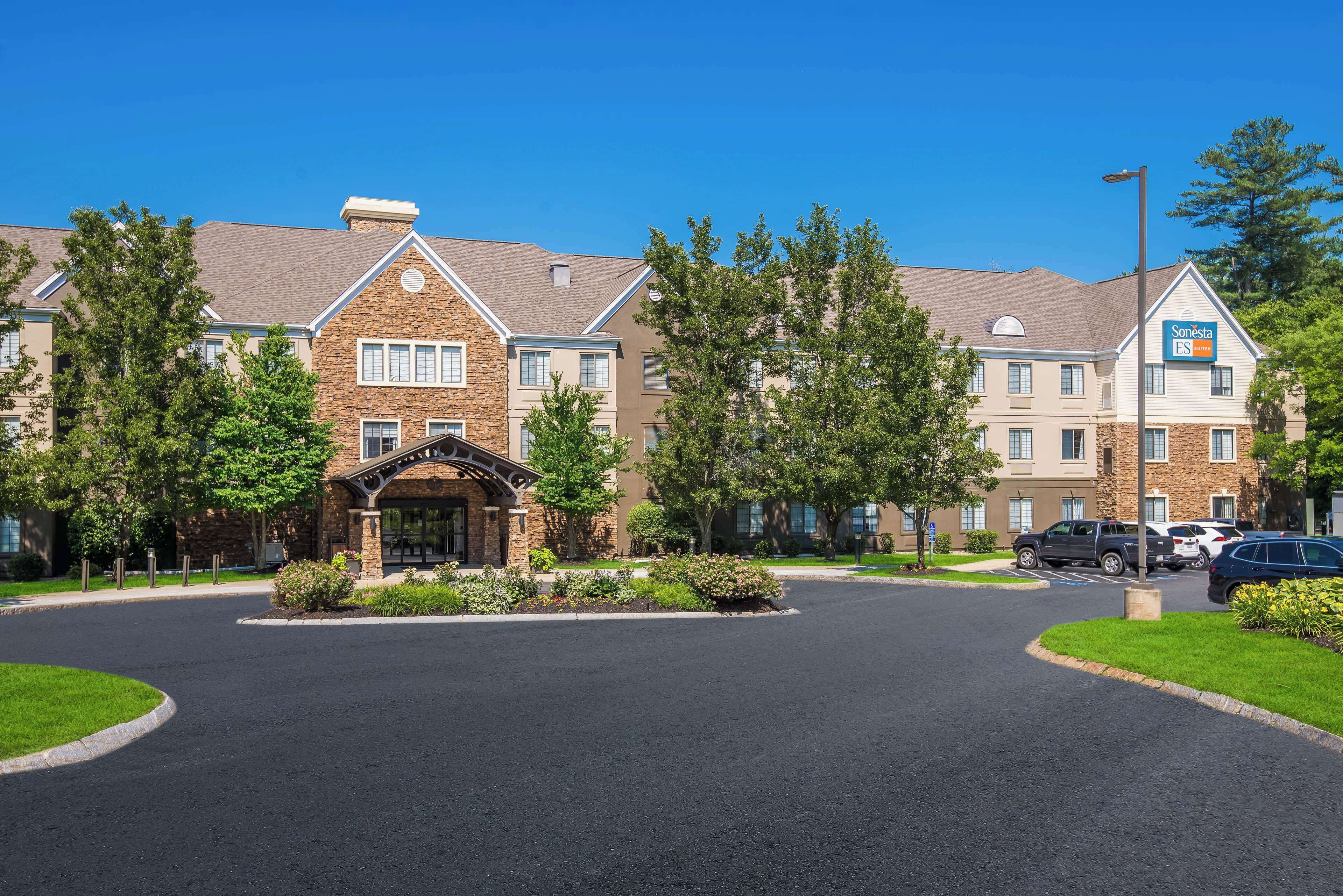 A hotel with a stone facade, a central entrance, and a parking area.