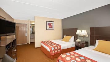 A hotel room with two beds, a television, a desk with a lamp, and a painting on the wall.