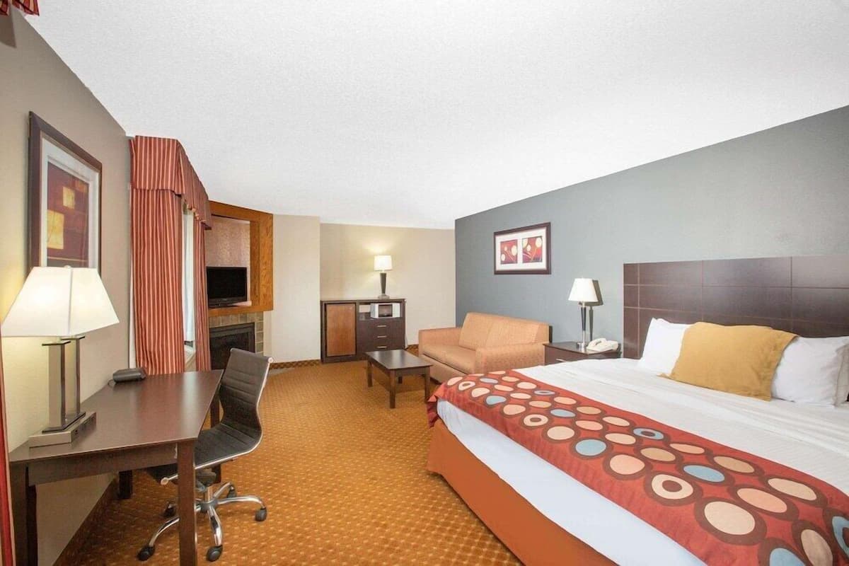 A hotel room with a bed, desk, chair, sofa, and a television.