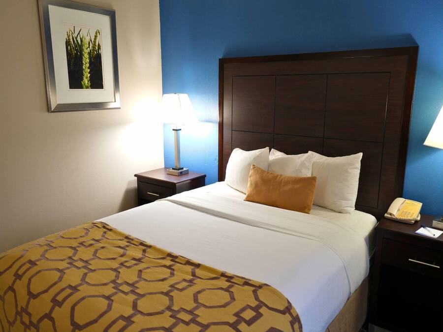 Una habitación de hotel con una cama grande, una mesita de noche con lámpara y un cuadro en la pared.