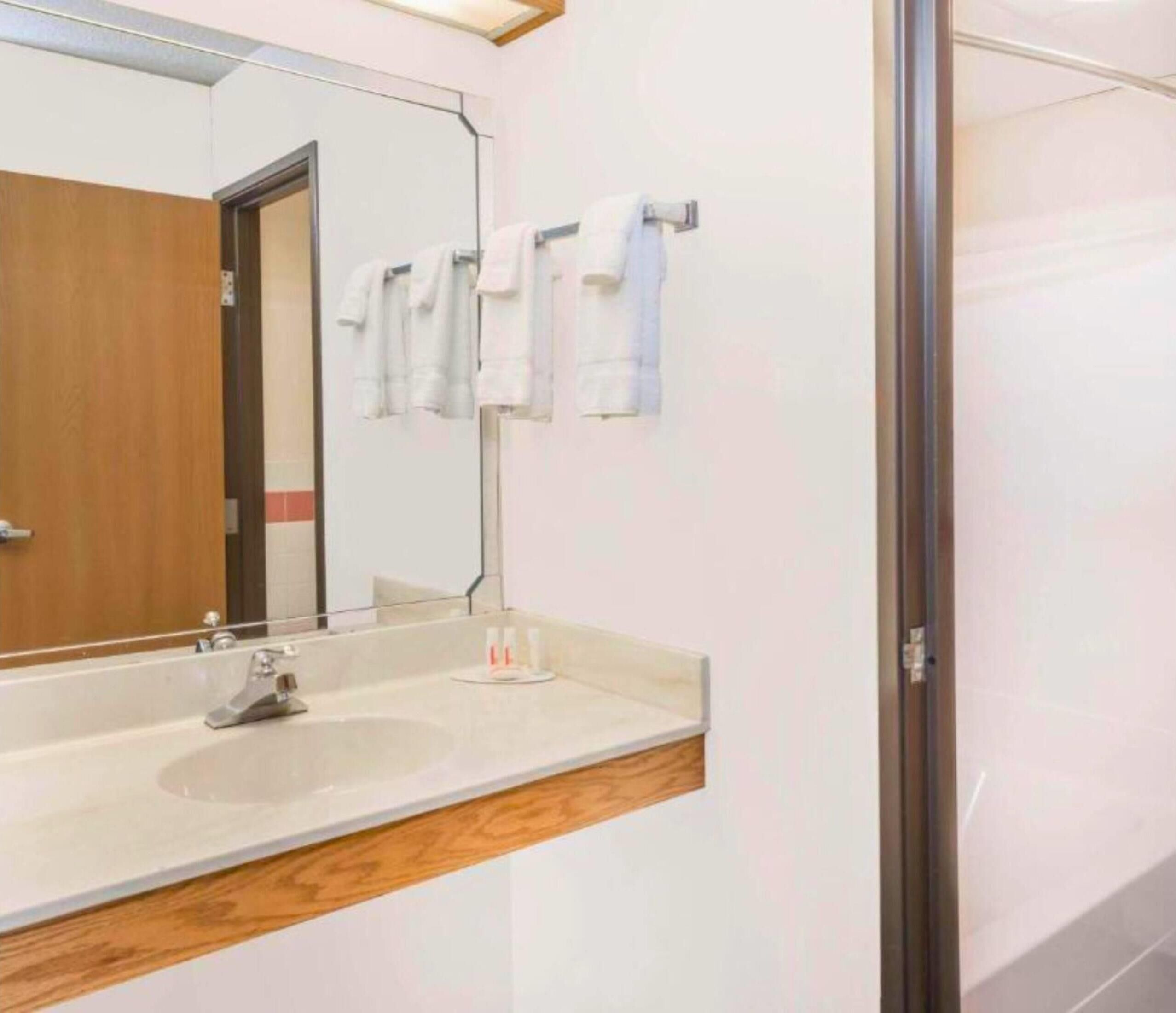 A bathroom with a large mirror, two sinks, and a wooden vanity.