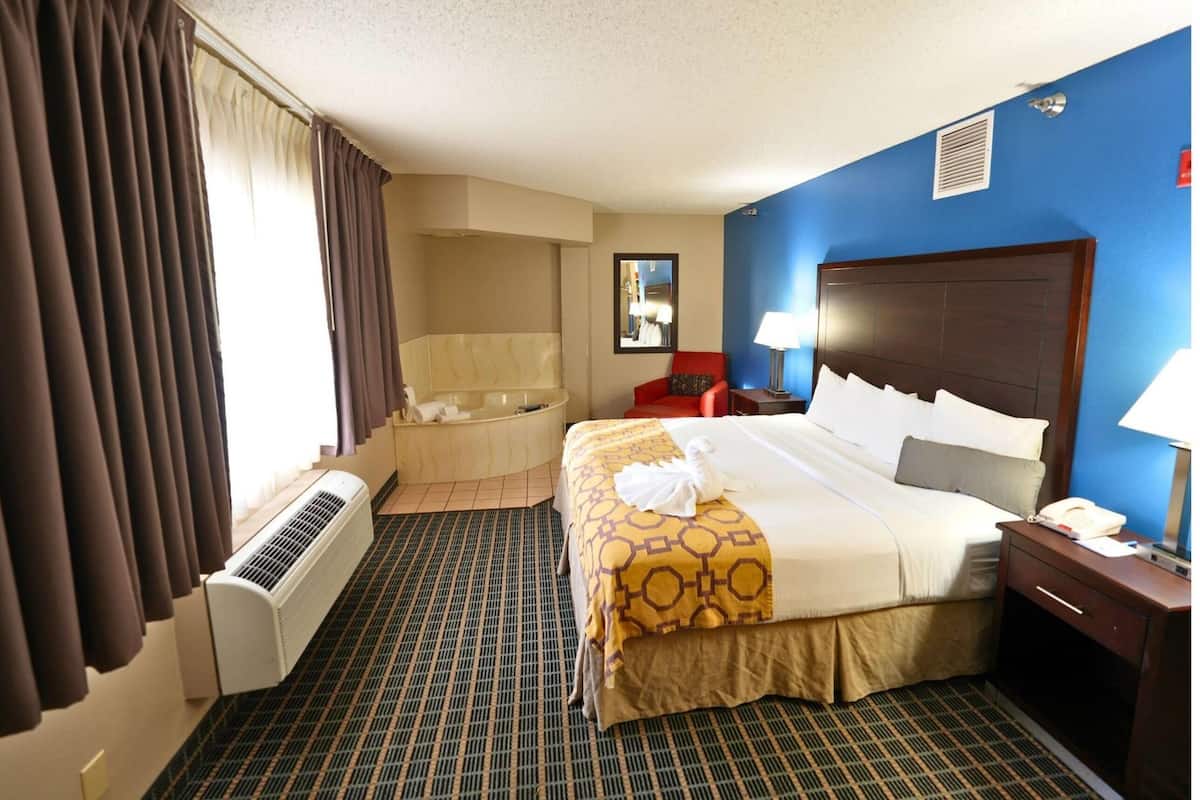 Habitación de hotel con una cama grande, una bañera incorporada, un escritorio y una silla.