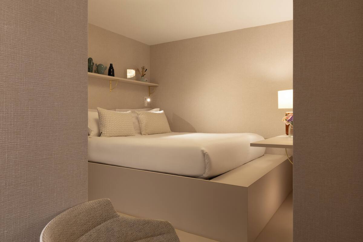 Una habitación de hotel moderna con cama, mesita de noche y una silla.