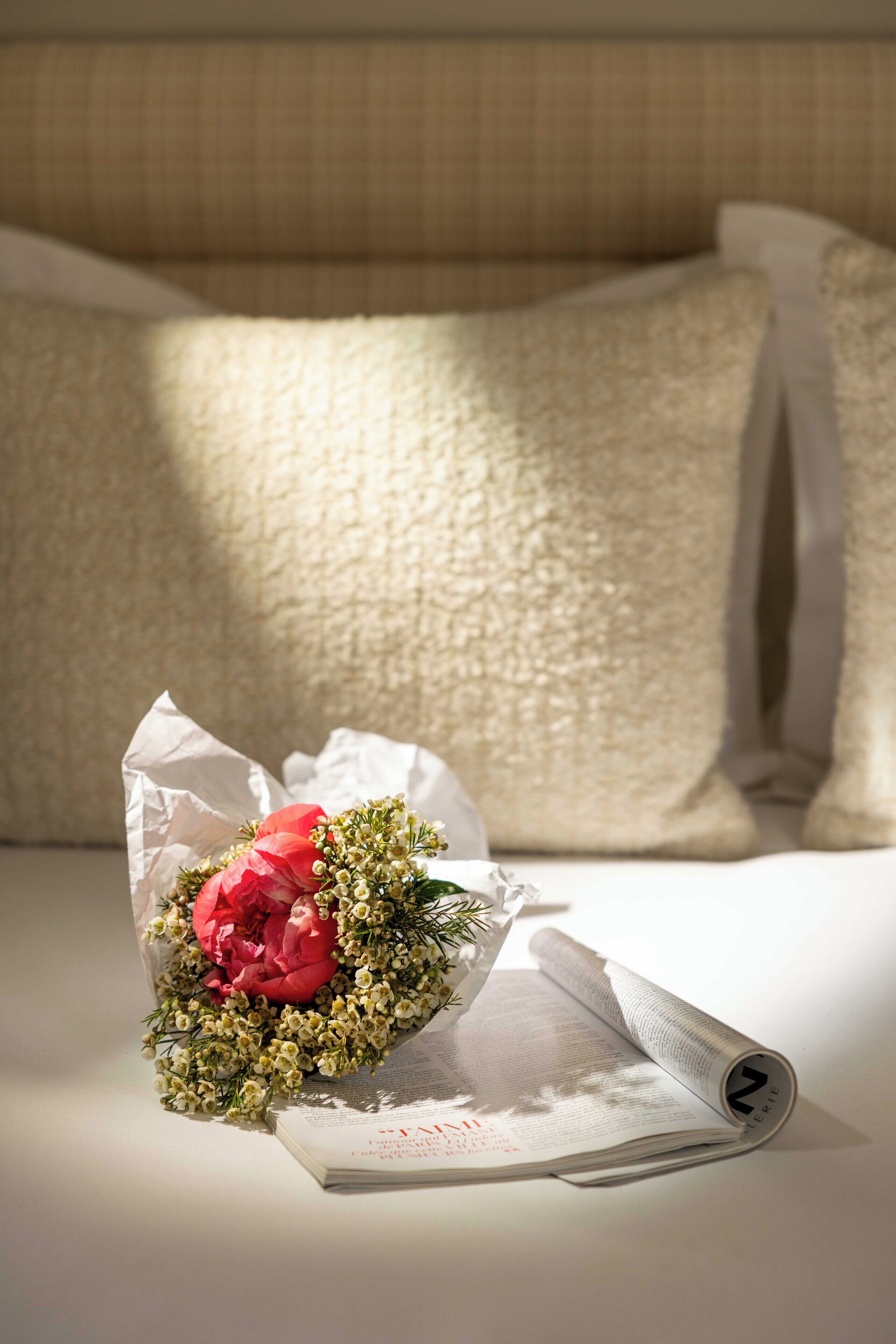 A bouquet of flowers on a bed with a newspaper.