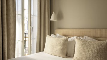 Une chambre d’hôtel avec un lit, des oreillers, une lampe suspendue et une vue sur un balcon.