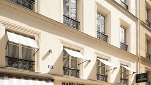 A multi-story hotel with a classic facade, featuring large windows and awnings. - Hôtel Madeleine Haussmann (Paris)