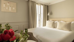 A hotel room with a large bed, a chair, a table, and a wall-mounted artwork. - Hôtel Madeleine Haussmann (Paris)