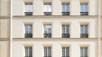 A multi-story hotel with balconies, awnings, and a sign reading 'MADELEINE HAUSSMANN HOTEL.'
