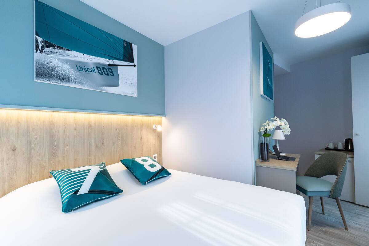 Une chambre d’hôtel moderne, équipée d’un lit, d’un bureau et d’une chaise.