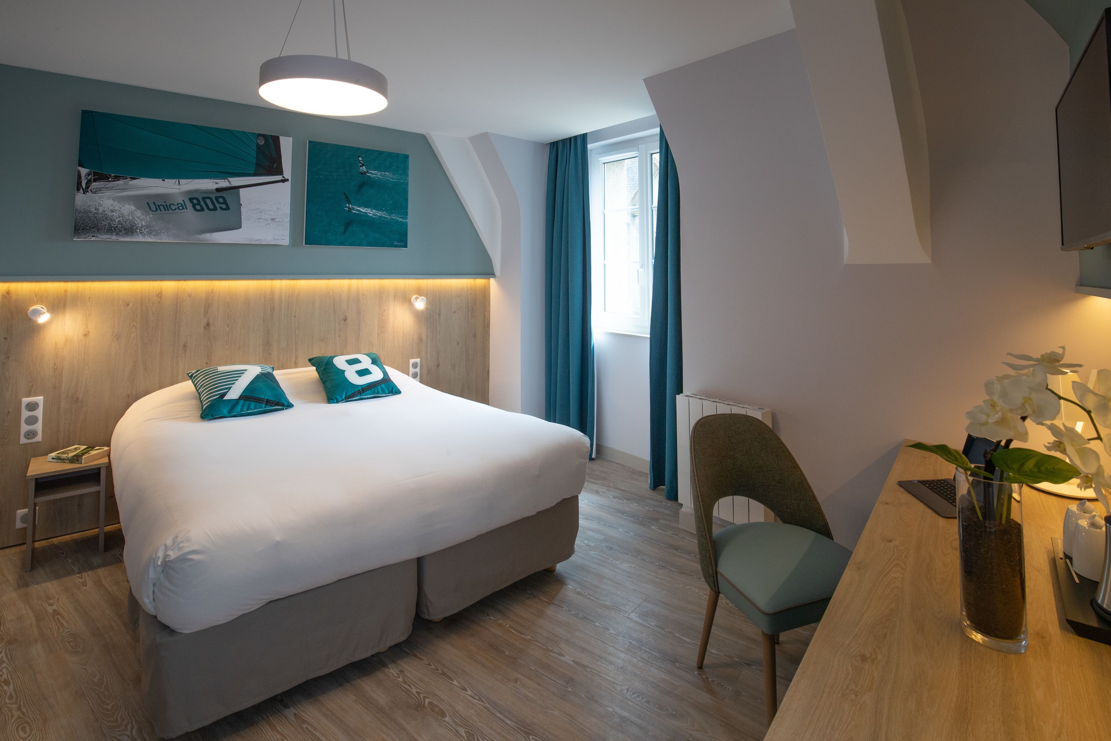 Una habitación de hotel moderna con una cama grande, un escritorio, una silla y un florero con flores.