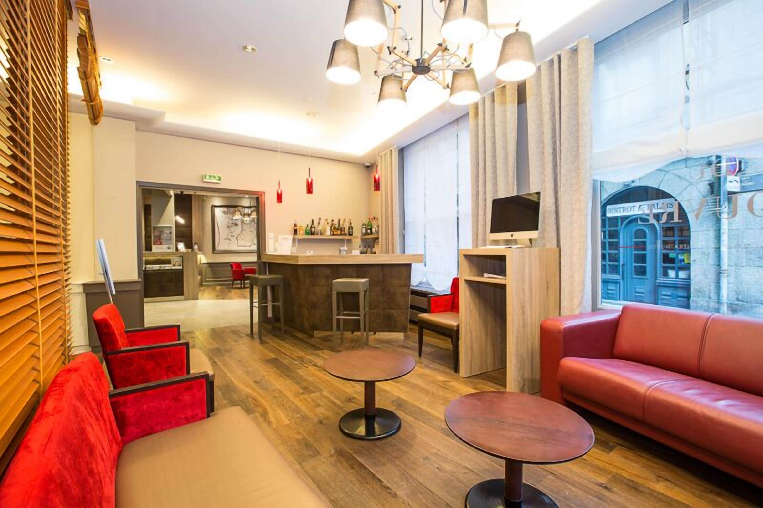 Un moderno vestíbulo de hotel con zona de bar, asientos y vistas a la calle.
