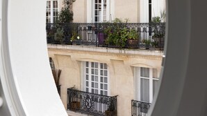 A view through a circular window of a multi-story building with balconies, windows, and a chimney. - Hotel Moderniste (Paris)