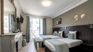 Et hotelværelse med to senge, en marmorpejs, et stort spejl og udsigt til gaden.