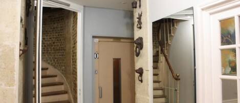Una escalera con barandilla de madera y una puerta con un pequeño ventanal.