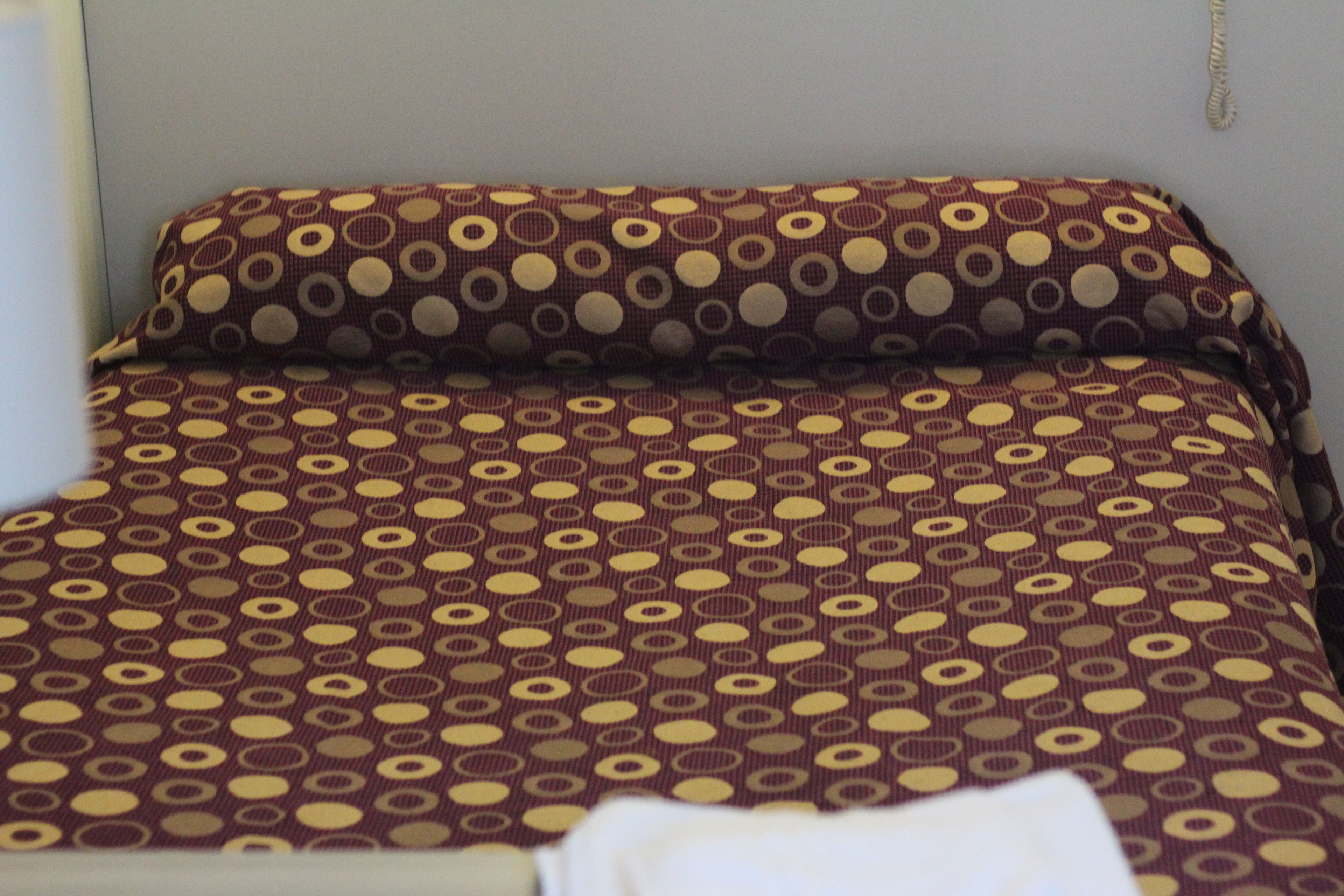 Un lit avec une couvre-lit à motifs et un oreiller.