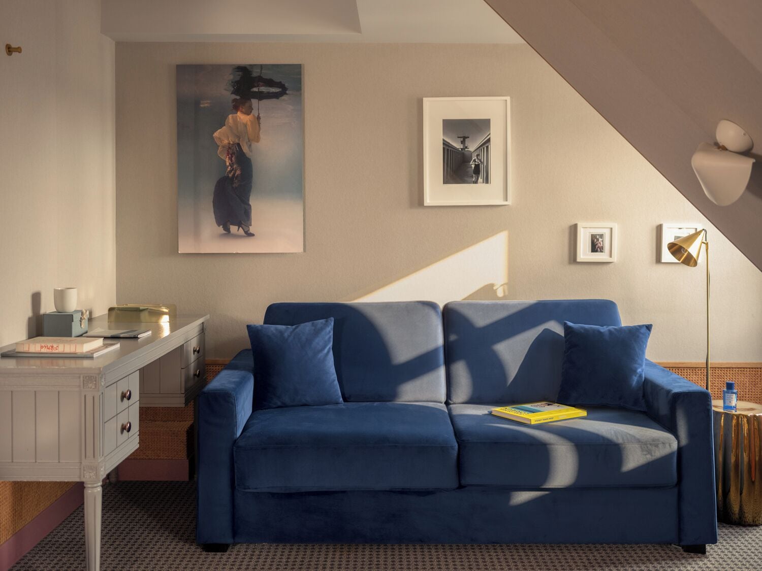 Ein modernes Wohnzimmer mit einem blauen Sofa, einer weißen Kommode und einem großen Bild an der Wand.