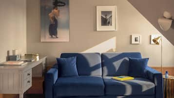 Ein modernes Wohnzimmer mit einem blauen Sofa, einer weißen Kommode und einem großen Bild an der Wand.