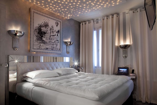 A modern bedroom with a large bed, decorative wall art, and ambient lighting. - Le Petit Madeleine Hôtel (Paris)