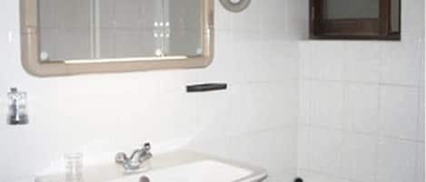 Une salle de bain avec un lavabo blanc, un miroir et une baignoire.