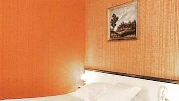 Une chambre d’hôtel avec un lit, un tableau au mur et une fenêtre.
