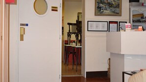A room with a white door, a clock on the wall, a framed picture, and a chair in the background. - Hôtel Avenir Vaugirard (Paris)