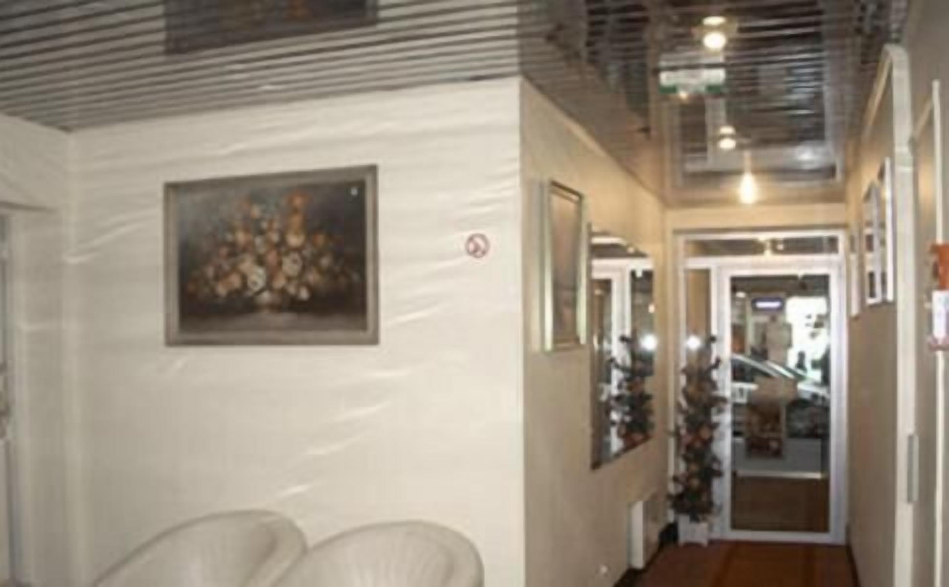 A hallway with a framed picture on the wall, a door with a sign, and a Christmas tree.