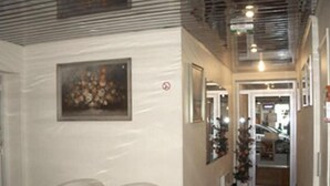 A hallway with two white armchairs, a framed picture on the wall, and a Christmas tree in the background. - Hôtel Avenir Vaugirard (Paris)
