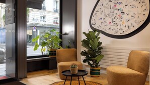 A hotel lobby with a large wall map, two armchairs, a small table with a cactus, and a window with a view of the street. - Hôtel Korner Opéra (Paris)