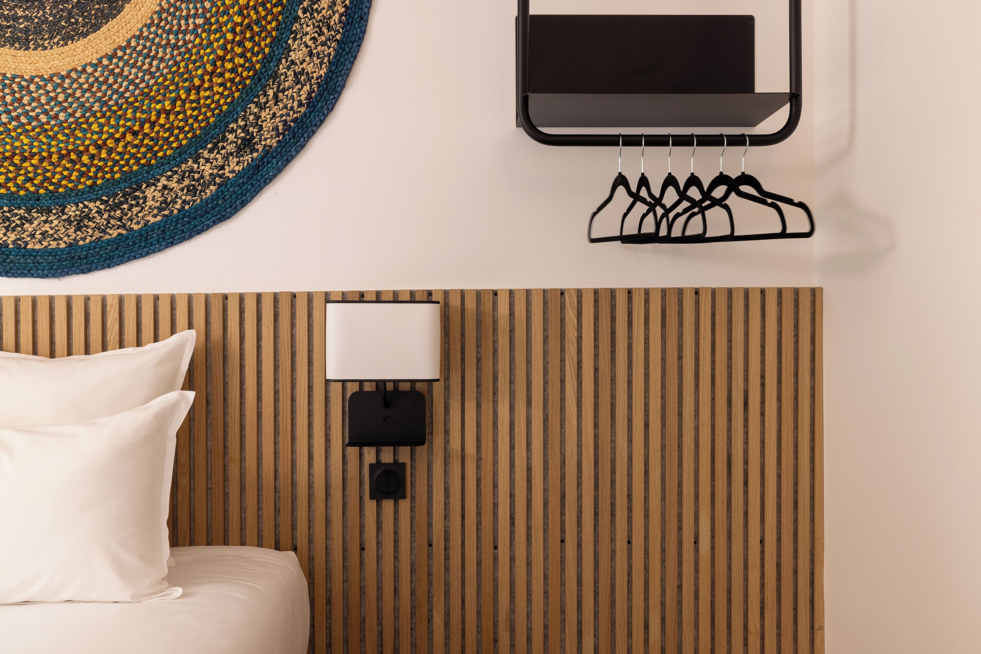 A hotel room with a bed, a wall-mounted TV, a wall-mounted lamp, and a wooden panel wall.