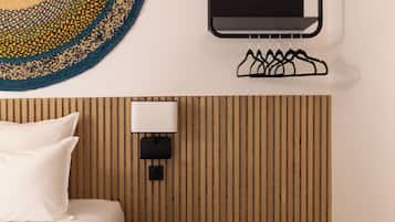 Een hotelkamer met een bed, een tv aan de muur, een lamp aan de muur en een wandpaneel van hout.